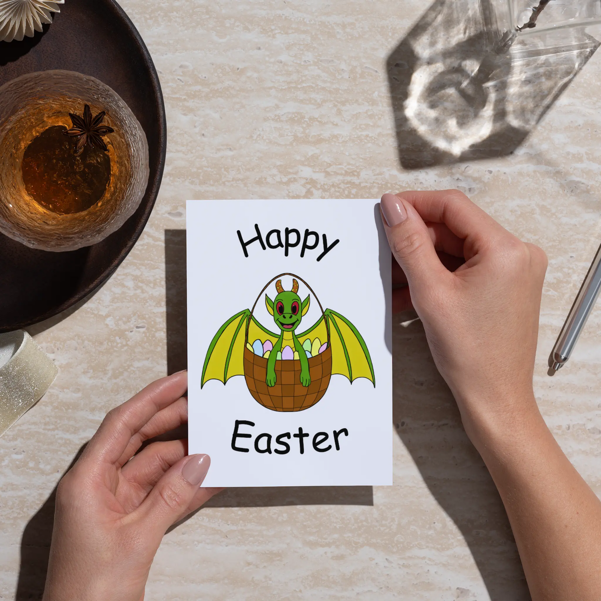 Person holding a 'Happy Easter' card with a dragon design on a table.